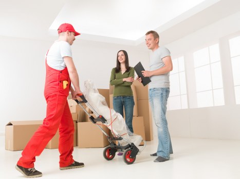 Professional piano movers preparing an upright piano for removal in Wimbledon